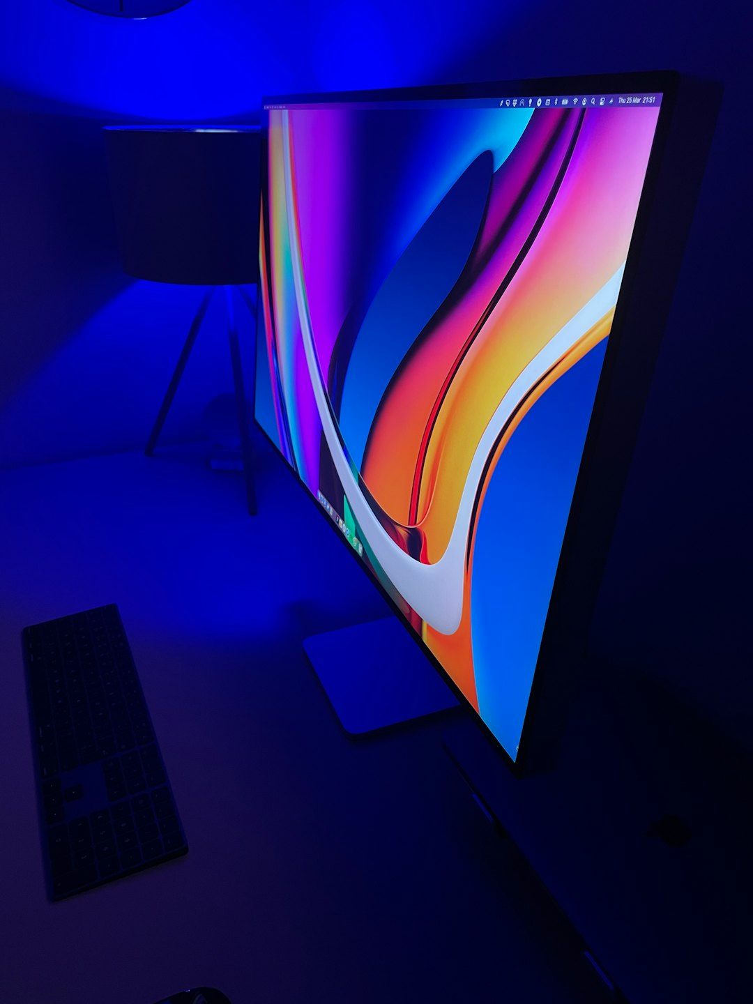 Modern computer monitor with colorful digital wallpaper on a desk.